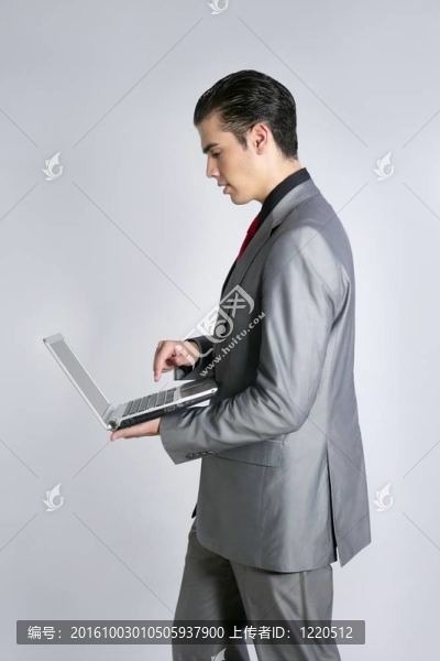 商人在灰色西裝控股筆記本電腦