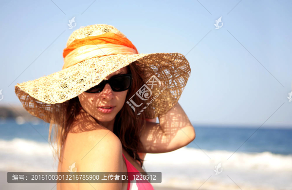 美麗的女人站在海邊戴著帽子