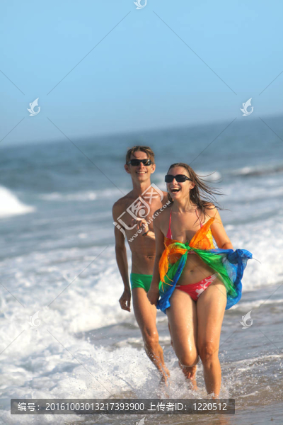 夏日快樂的情侶在海灘上跑步