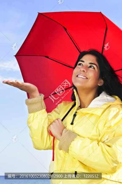 美麗的年輕女子在雨衣傘檢查雨