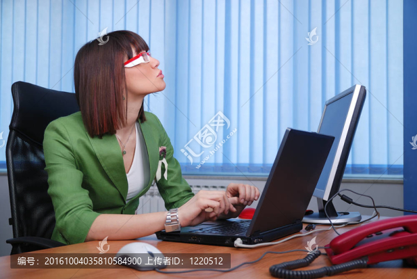微笑的年輕女商人正在辦公室里一臺(tái)筆記本電腦。