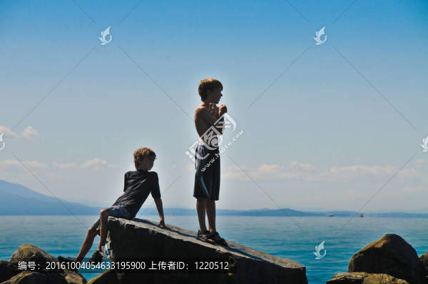 兩個男孩站在一個湖的巖石上