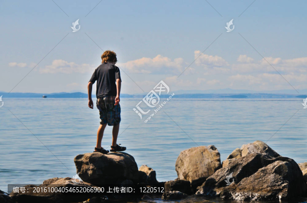 男孩走在湖上的巨石上