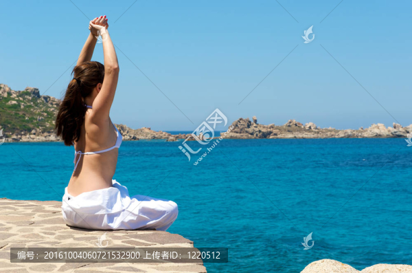 漂亮的女人和一個在撒丁島海景做放松練習；意大利