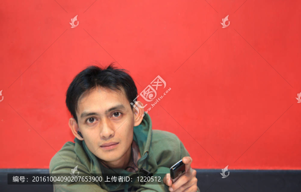 年輕男子手持手機(jī)在紅色背景