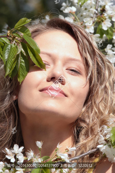 漂亮的金發(fā)女人在樹與白色的花之間