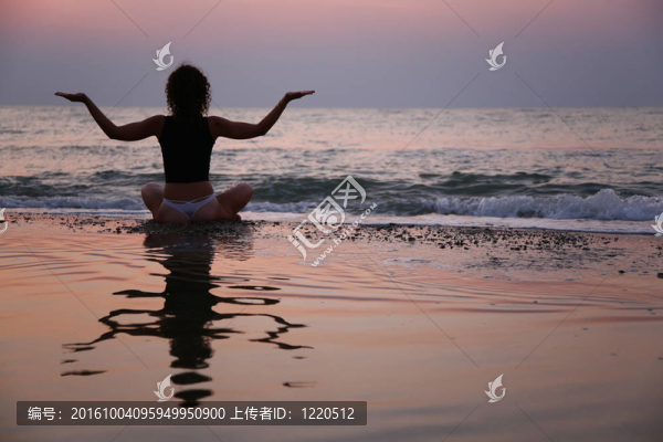夕陽下的年輕女人坐在沙灘上