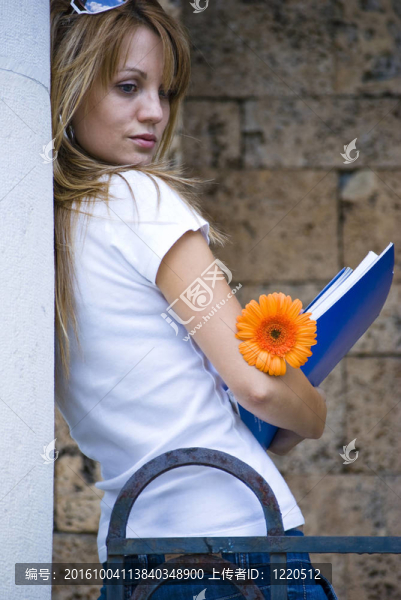美麗的年輕婦女與書籍和鮮花