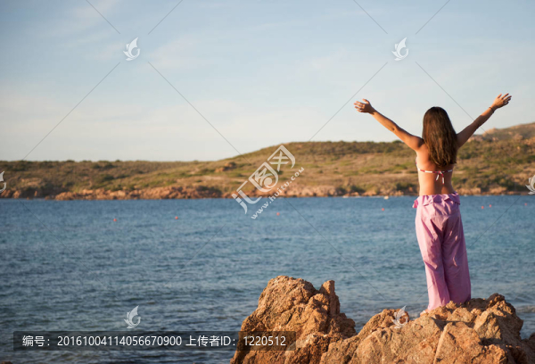 女人在巖石上放松與海景