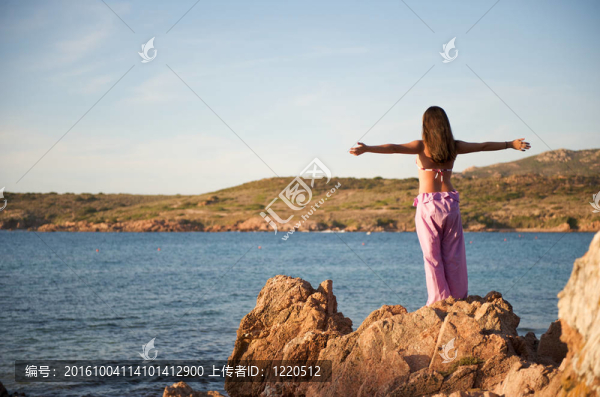 女人在巖石上放松與海景