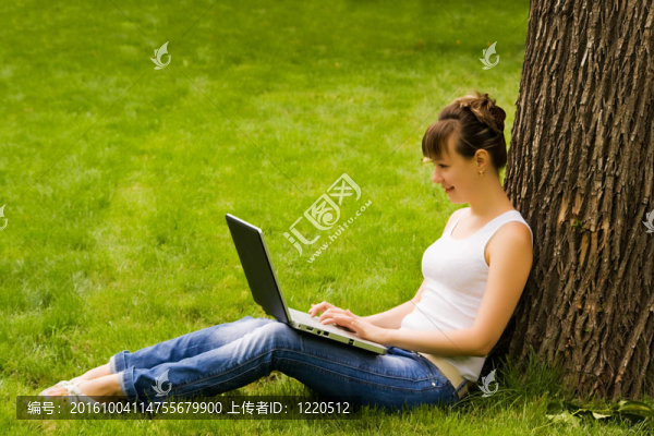 年輕女子在草地上帶著筆記本