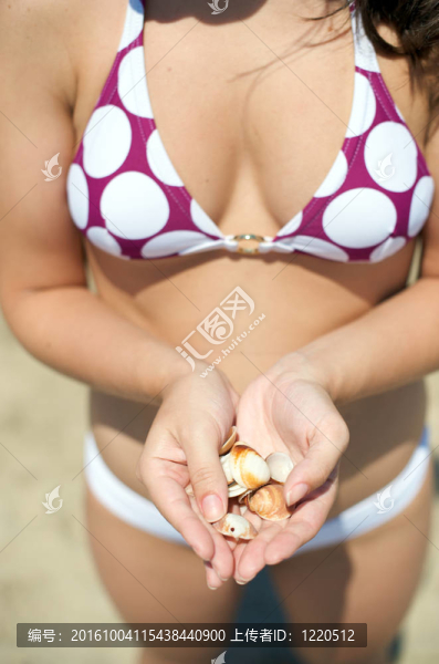 在海灘上玩貝殼的女人