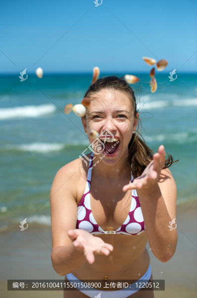 在海灘上玩貝殼的女人