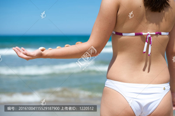 在海灘上玩貝殼的女人