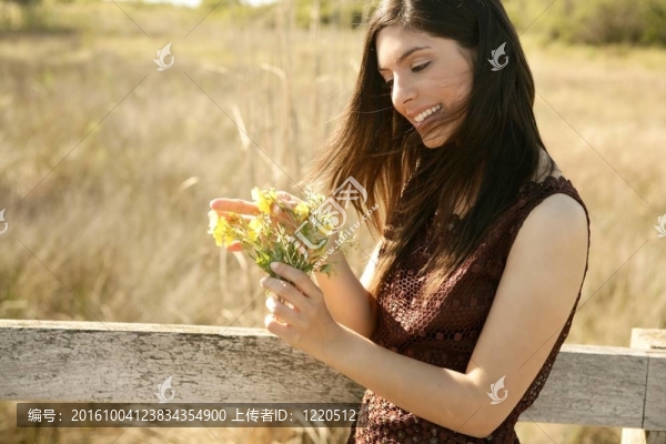 美麗的女人在金色的戶外；黃色的花
