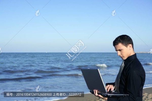英俊的年輕商人電腦海灘
