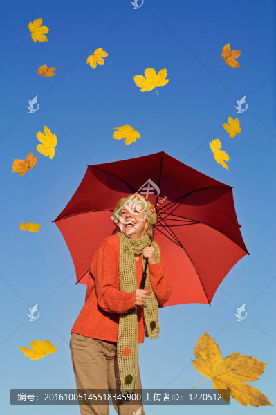 幸福的女人帶著雨傘和飄落的黃葉