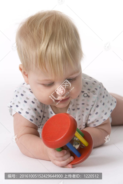 女嬰趴在肚子上看著玩具