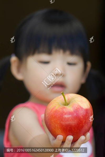 一個(gè)小孩拿著一個(gè)紅蘋果