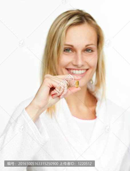 迷人的年輕女子拿著黃色藥丸