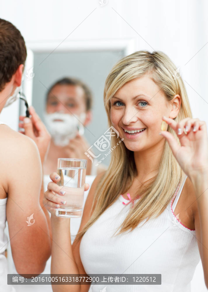 微笑的女人拿著藥丸和男人剃須