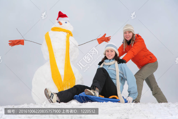 兩個(gè)女孩用塑料雪橇和雪人