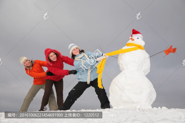 三個(gè)年輕女孩用黃色圍巾拉雪人