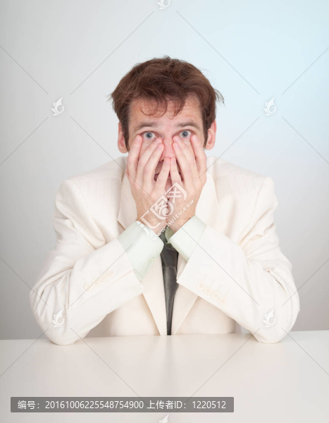 穿著白色套裝的年輕悲傷的人坐在桌子旁