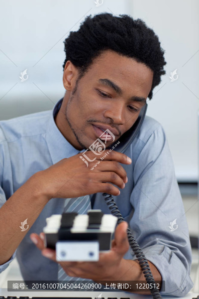 微笑的非洲商人在電話里看卡片持有人