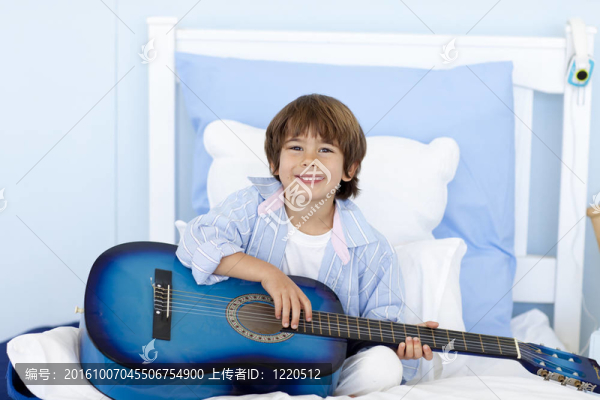 快樂(lè)的小男孩在床上彈吉他