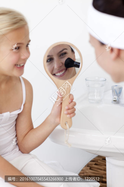 微笑的女兒拿著鏡子和媽媽化妝