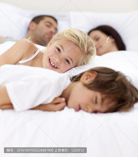 小女孩微笑著在床上欺騙她的家人的睡眠