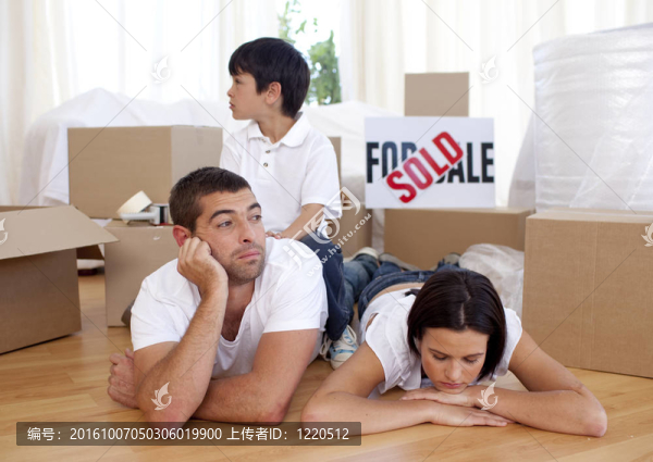 疲憊的家庭在買新房子后在地板上放松
