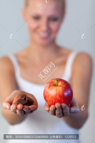 美麗的女人拿著巧克力和蘋(píng)果聚焦蘋(píng)果