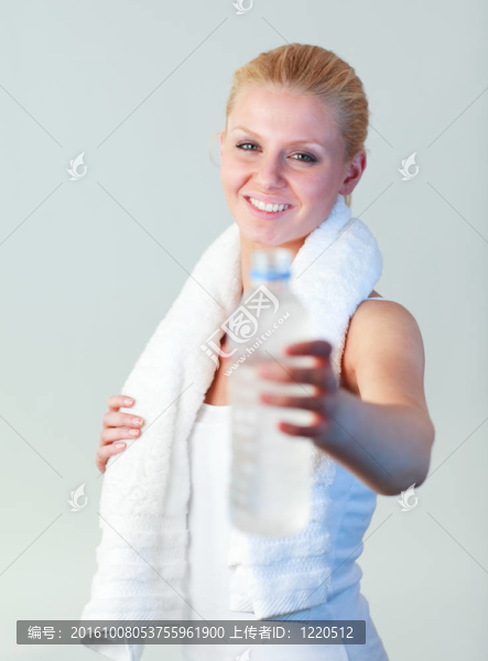 一個(gè)迷人的女人拿著一瓶水和毛巾專注于女人的肖像