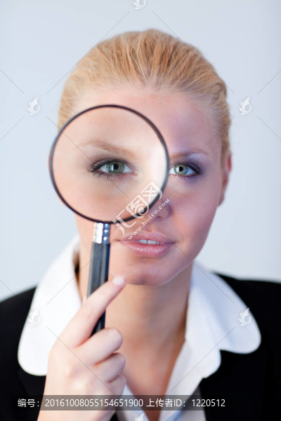 嚴(yán)肅的商業(yè)女性通過放大鏡看格拉斯