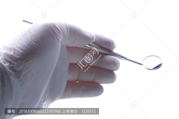 牙醫(yī)用戴手套的手抓住傾斜的鏡子