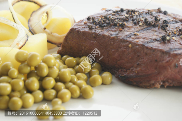 烤胡椒牛排配些豌豆和土豆在白盤(pán)子上