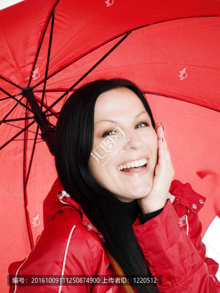 微笑的黑發(fā)女人在秋天；防雨的衣服打著傘