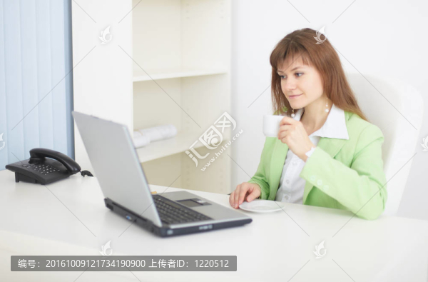 女人坐在桌上，笔记本电脑和咖啡