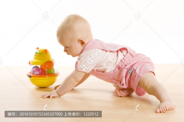 女嬰向地板上的玩具爬行