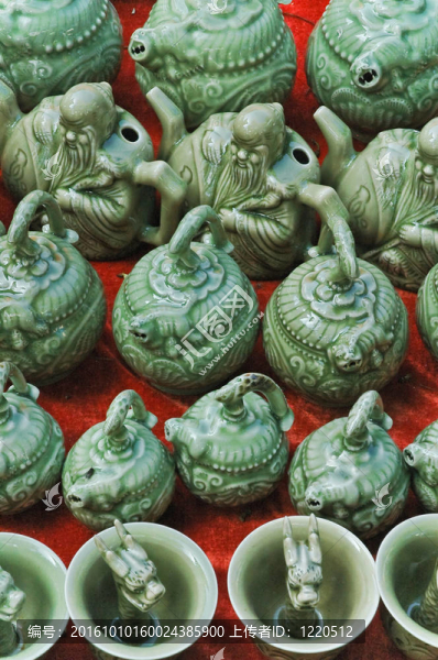 傳統(tǒng)的綠色琉璃東方陶瓷茶壺和茶杯在中國市場在紅色的背景上。