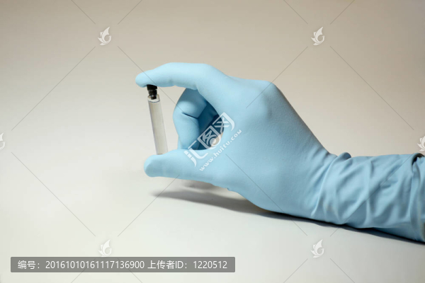 戴著手套的手拿著一瓶透明的液體
