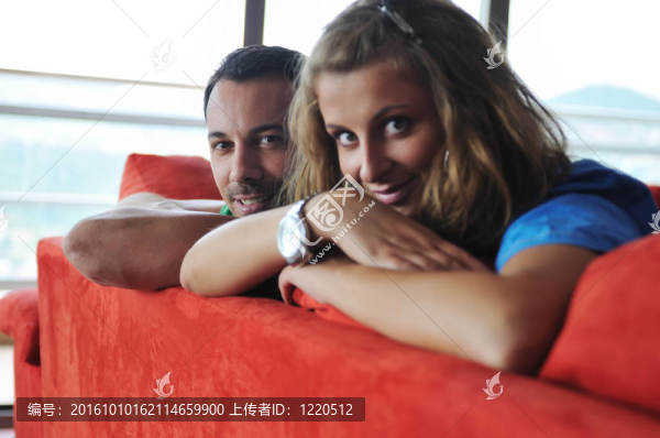 幸福的一對夫婦在紅色的沙發(fā)上放松