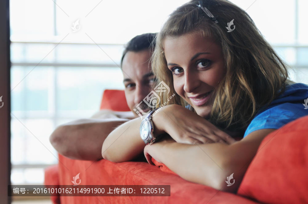 幸福的一對夫婦在紅色的沙發(fā)上放松