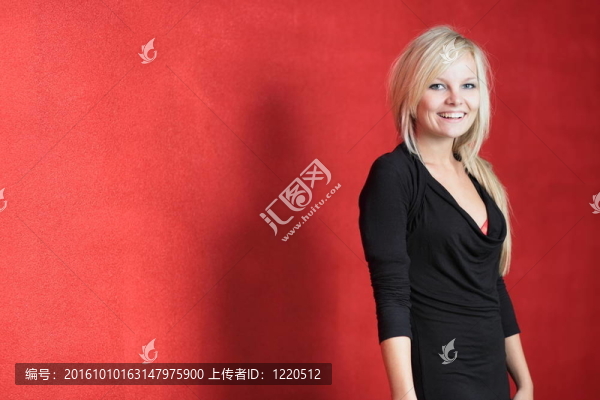一個漂亮的金發(fā)女郎擺在紅墻前的畫像