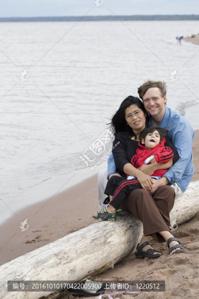 混血兒的丈夫和妻子抱著他們的孩子在沙灘上