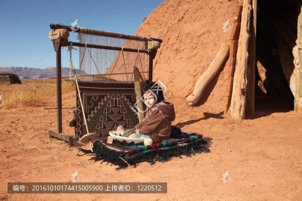 納瓦霍人的孩子坐在旁邊的傳統(tǒng)地毯的制作工具