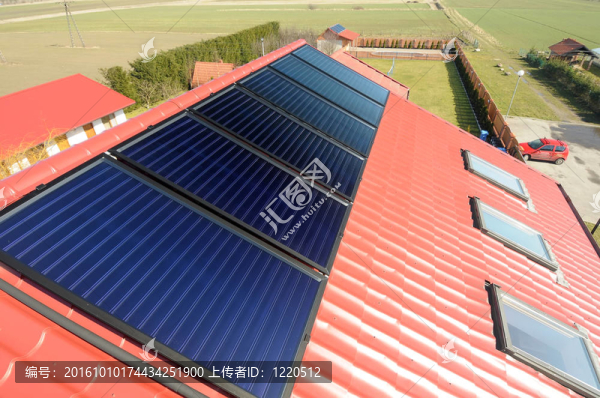 紅屋頂與太陽(yáng)能電池板的關(guān)閉。背景綠地。