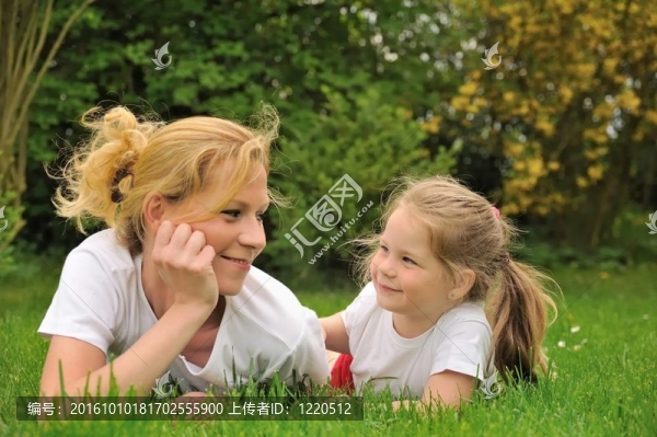 年輕的母親和女兒躺在草地上